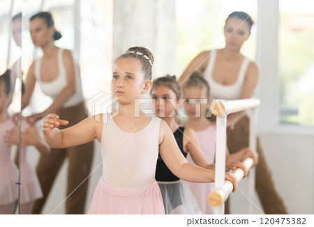 Woman teacher corrects girls in batman tandu movement Woman teacher corrects girls in batman tandu movement 120475382