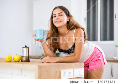 Young woman drinking morning coffee in home kitchen 120475384