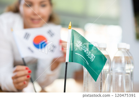 Employee of delegation prepares negotiating table - sets up flag of Saudi Aarabia and South Korea 120475391