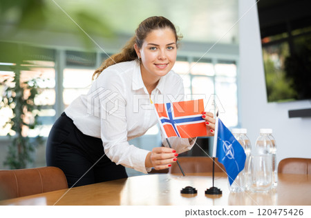 Young female secretary preparing room for international negotiations between nato and norway Young female secretary preparing room for international negotiations between nato and norway 120475426