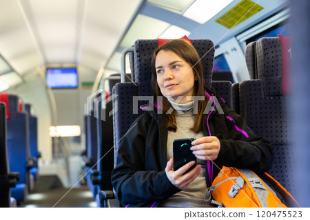 Woman using her smartphone while traveling by train Woman using her smartphone while traveling by train 120475523