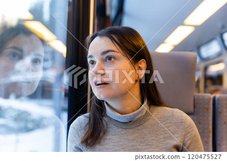Astonished woman looking through train window while journeying 120475527