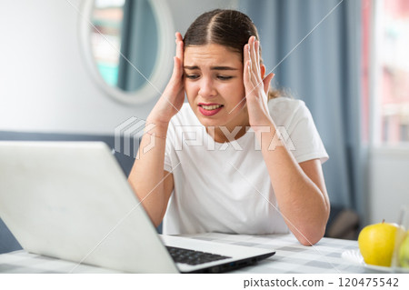 Young woman with headache working at home 120475542