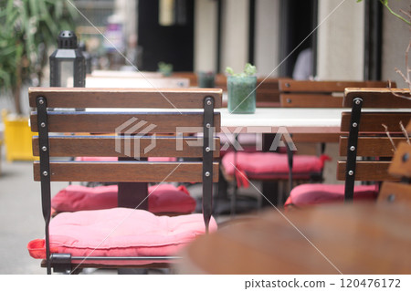 Charming and Inviting Outdoor Cafe Seating Featuring Wooden Chairs and Soft Cushions Charming and Inviting Outdoor Cafe Seating Featuring Wooden Chairs and Soft Cushions 120476172