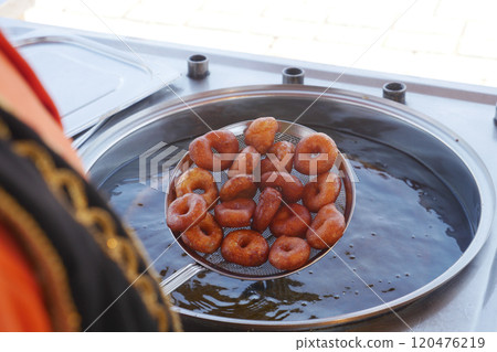Freshly fried donuts are being prepared in hot oil, creating a delightful aroma in the air Freshly fried donuts are being prepared in hot oil, creating a delightful aroma in the air 120476219