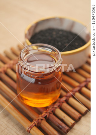 Black Seeds and Their Oil Beautifully Arranged in a Rustic Wooden Bowl for Culinary Uses Black Seeds and Their Oil Beautifully Arranged in a Rustic Wooden Bowl for Culinary Uses 120476563