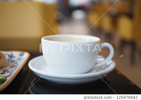 An Elegant White Coffee Cup Placed on a Saucer in a Contemporary Cafe Setting with Style An Elegant White Coffee Cup Placed on a Saucer in a Contemporary Cafe Setting with Style 120476682