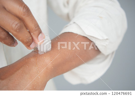 Man rubbing ice cube on his hand. Man rubbing ice cube on his hand. 120476691