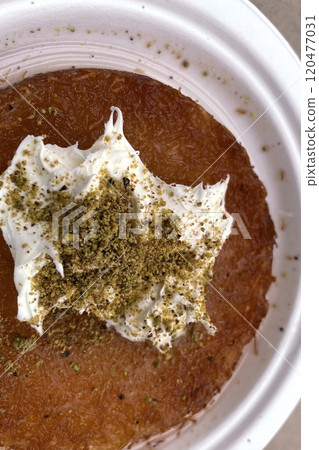 Traditional Turkish Dessert Kunefe with Clotted Cream and Crushed Pistachios.The image shows a portion of Kunefe, a traditional Turkish dessert. The knefe is topped with clotted cream Traditional Turkish Dessert Kunefe with Clotted Cream and Crushed Pistachios.The image shows a portion of Kunefe, a traditional Turkish dessert. The knefe is topped with clotted cream 120477031