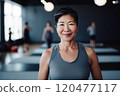 Portrait of smiling Asian woman standing on exercise mat in gym. Selective Focus 120477117