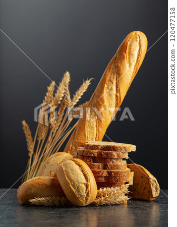 Bread and wheat ears on a black background. 120477158