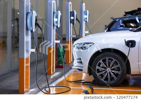 EV charger and electric car, Electric car charger station for charge ev battery, Plug for vehicle with electric engine, EV charger clean energy, Charging point at car parking lot department store. EV charger and electric car, Electric car charger station for charge ev battery, Plug for vehicle with electric engine, EV charger clean energy, Charging point at car parking lot department store. 120477174