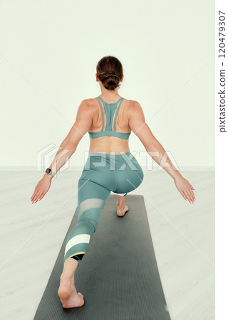 Fitness Trainer in Deep Lunge Pose with Outstretched Arms 120479307