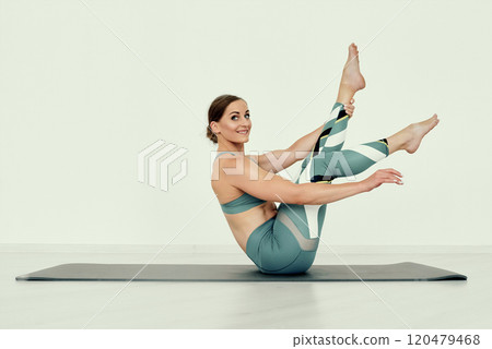 Smiling Fitness Trainer in Modified Boat Pose with Extended Leg Smiling Fitness Trainer in Modified Boat Pose with Extended Leg 120479468