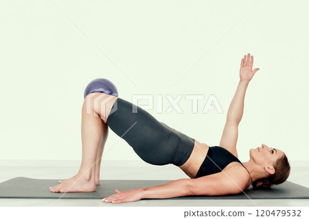 Fitness Trainer in Elevated Glute Bridge with Arm Raise 120479532