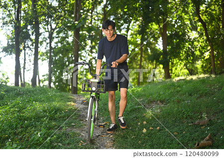 Smiling asian man walking with bicycle on a forest path. Recreation and outdoor activity concept Smiling asian man walking with bicycle on a forest path. Recreation and outdoor activity concept 120480099