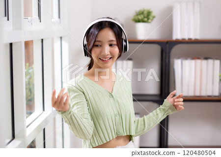 Portrait happy young woman wearing headphones listening music while standing with fun. Portrait happy young woman wearing headphones listening music while standing with fun. 120480504