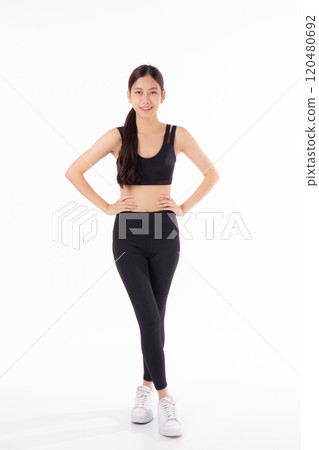 Portrait of beautiful young asian woman in sportwear smile and showing waist and abs isolated. 120480692