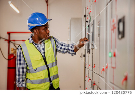 Electrical engineer working in control room. Electrical engineer man checking Power Distribution Cabinet in the control room Electrical engineer working in control room. Electrical engineer man checking Power Distribution Cabinet in the control room 120480776