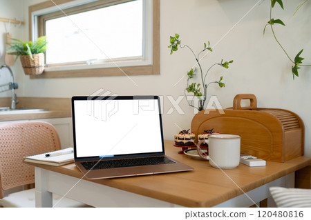 Laptop, coffee cup and decorated cupcakes on a wooden table in the kitchen Laptop, coffee cup and decorated cupcakes on a wooden table in the kitchen 120480816