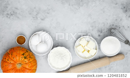 Baking ingredients including flour, butter, sugar, spices, eggs and pumpkin arranged on a gray background. Seasonal autumn baking 120481852