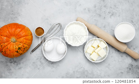 Baking ingredients including flour, butter, sugar, spices, eggs and pumpkin arranged on a gray background. Seasonal autumn baking 120481854