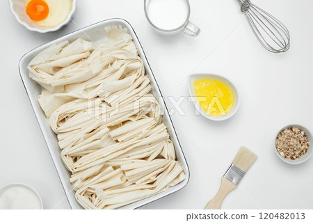 Filo dough in a baking dish near Crinkle Cake butter for buttering Filo dough in a baking dish near Crinkle Cake butter for buttering 120482013