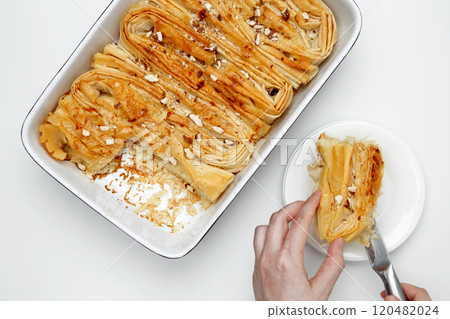Finished Crinkle Cake made from phyllo dough is cut with a knife 120482024