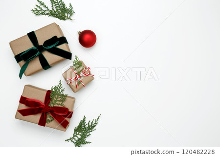 Wrapped Christmas gifts with green thuja branches creating a festive, natural holiday scene Wrapped Christmas gifts with green thuja branches creating a festive, natural holiday scene 120482228