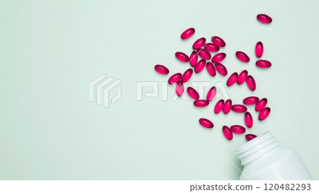 Concept of medicine, healthcare, and pharmaceutical industry. Bottles with red pills scattered on light blue background Concept of medicine, healthcare, and pharmaceutical industry. Bottles with red pills scattered on light blue background 120482293