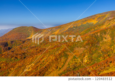 Mount Kurikoma, which straddles the three prefectures of Miyagi, Iwate, and Akita, features vibrant autumn foliage and blue skies covering the slopes as seen from the central course. Mount Kurikoma, which straddles the three prefectures of Miyagi, Iwate, and Akita, features vibrant autumn foliage and blue skies covering the slopes as seen from the central course. 120483512