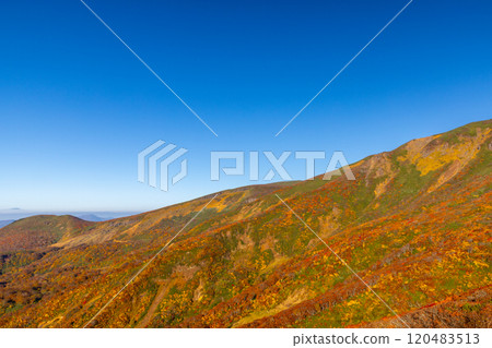 Mount Kurikoma, which straddles the three prefectures of Miyagi, Iwate, and Akita, features vibrant autumn foliage and blue skies covering the slopes as seen from the central course. Mount Kurikoma, which straddles the three prefectures of Miyagi, Iwate, and Akita, features vibrant autumn foliage and blue skies covering the slopes as seen from the central course. 120483513