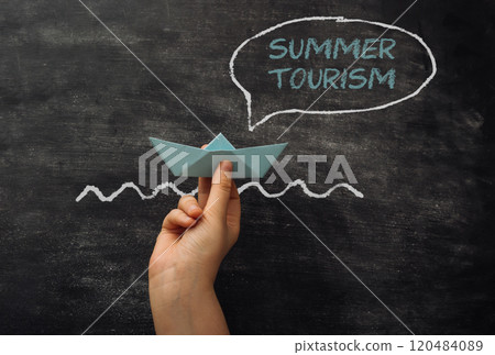 Hand holding a paper boat in front of a chalkboard Hand holding a paper boat in front of a chalkboard 120484089