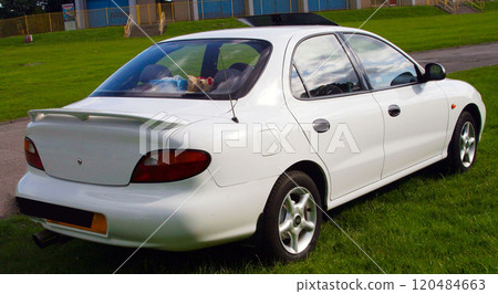 sleek classic white sedan parked on a grassy field, showcasing its elegant design and functionality in an outdoor environment sleek classic white sedan parked on a grassy field, showcasing its elegant design and functionality in an outdoor environment 120484663