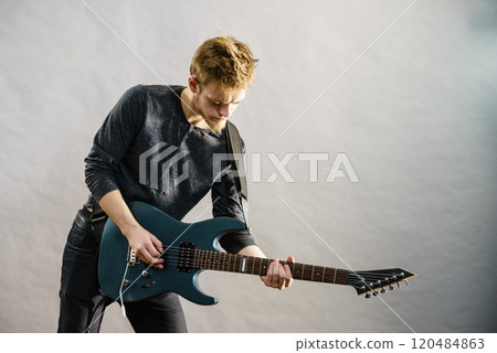 Young man playing electric guitar 120484863