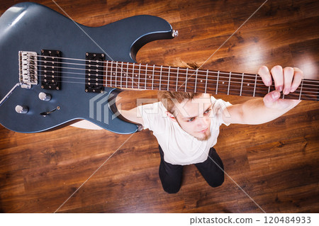 Proud man raising his electric guitar 120484933