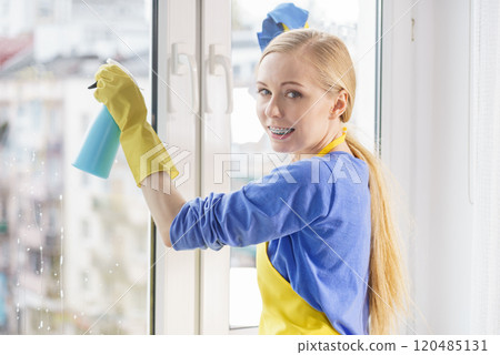 Woman cleaning window at home 120485131