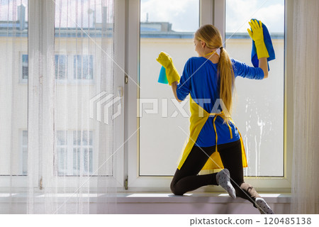 Woman cleaning window at home 120485138