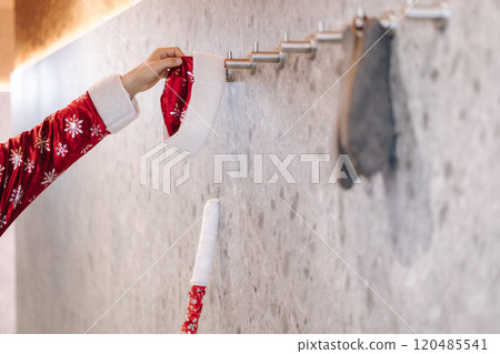 Santa figure in a festive robe hanging their candy cane staff on a wall hook, preparing for rest after holiday activities. 120485541