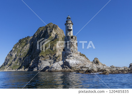 Aniva - The abandoned lighthouse in the Sakhalin Island, Korsakov district, Russia. Pacific ocean. The abandoned lighthouse Island Blue sea. Beautiful view. Blue sky and blue Pacific ocean. 120485835