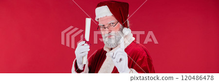 Portraying Santa Claus Holding Paper Against Red Backdrop 120486478