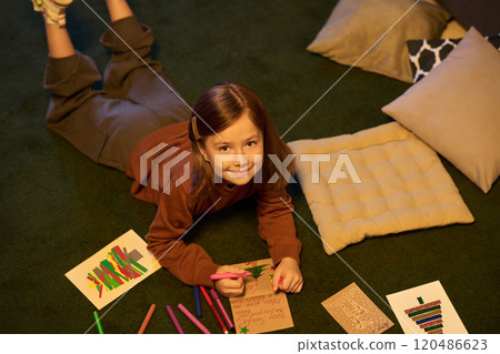 Young Girl Drawing on Green Carpet During Playtime Young Girl Drawing on Green Carpet During Playtime 120486623
