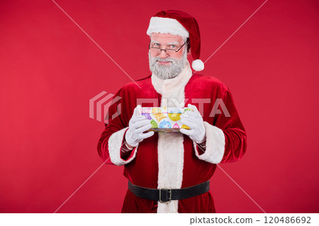 Portrait of Senior Man Wearing Santa Costume Holding Gift Box 120486692