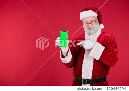 Santa Claus Pointing at Smartphone Screen Against Red Background 120486694