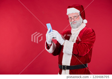 Portrait of Santa Claus Using Smartphone on Red Background 120486705