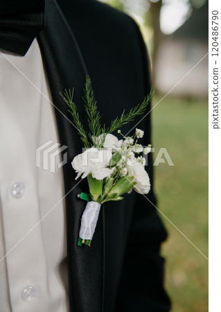 A man in a tuxedo has a white flower boutonniere on his jacket A man in a tuxedo has a white flower boutonniere on his jacket 120486790