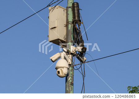 A camera mounted on a pole with a clear blue sky in the background A camera mounted on a pole with a clear blue sky in the background 120486865