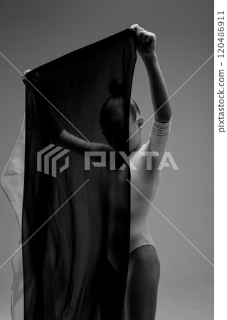 A striking black and white photograph depicting a woman holding a black cloth 120486911