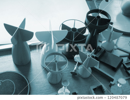 Prototype model of rocket bomb tip printed on 3D printer. Small models of tail fins, tail cone printed on 3D printer from molten plastic on table. New modern innovation printing technology 120487079