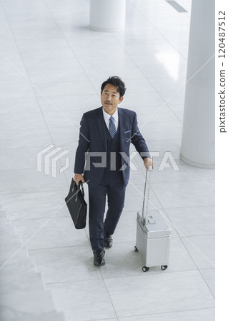 商人出差形象：50多歲的商人提著手提箱和商務包行走 120487512